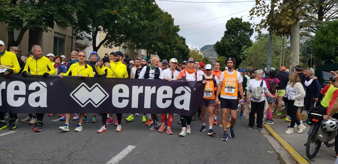 Les Cenbornards de Millau : récit de deux kinés déficients visuels qui ont défié les 100 km 2 Le cortège avec la banderolle tenue par Hervé, Nicolas et leurs guides au premier rang, en route pour le départ des 100km de Millau